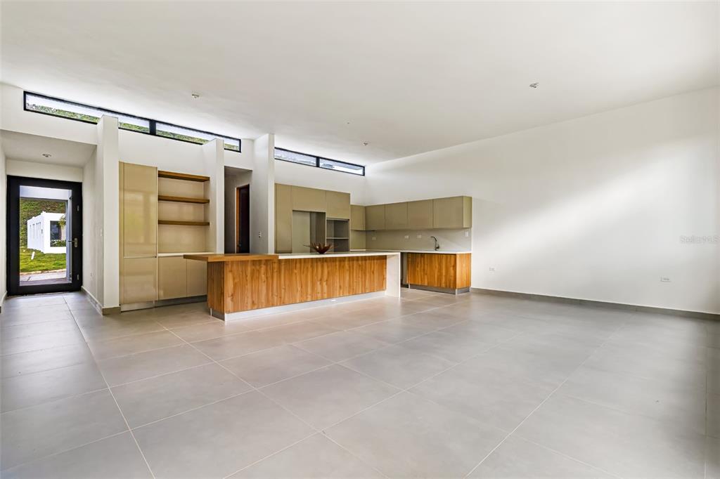 A modern kitchen features light wood cabinetry, a large island, and large gray floor tiles — 238 URB. MONTEAZUL, GUAYNABO, PR