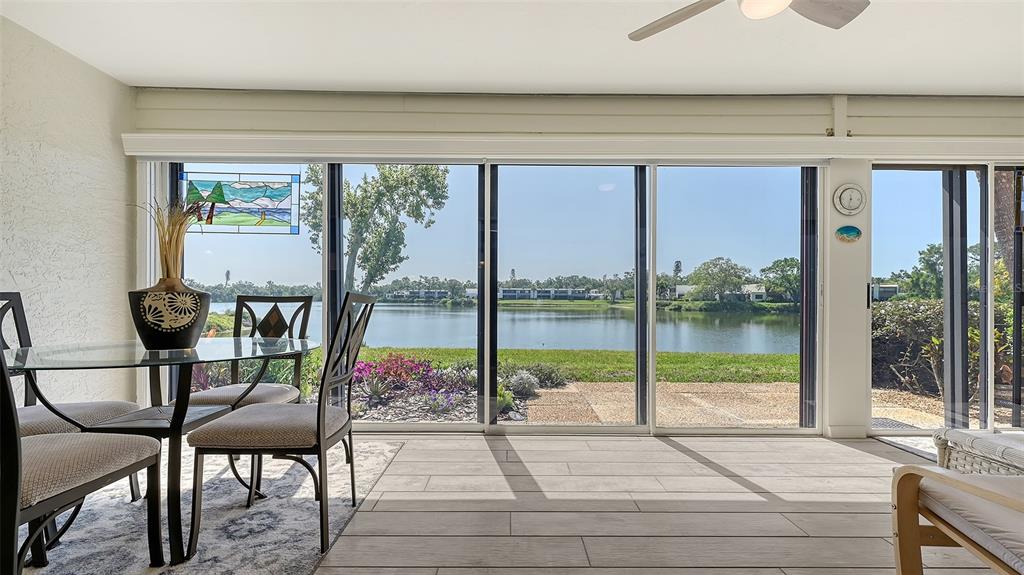A sunroom with tile floors and a dining set overlooks a lake through sliding doors — 515 SPRING LAKES BOULEVARD UNIT 515, BRADENTON, FL