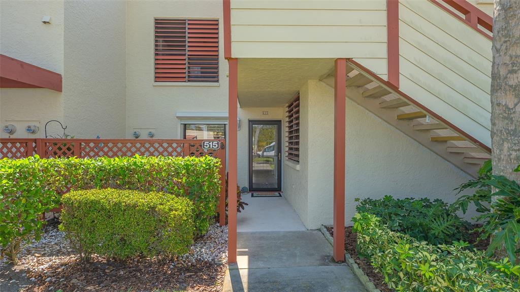 The exterior of a ground-floor apartment unit features a front door, stairs, and landscaping — 515 SPRING LAKES BOULEVARD UNIT 515, BRADENTON, FL