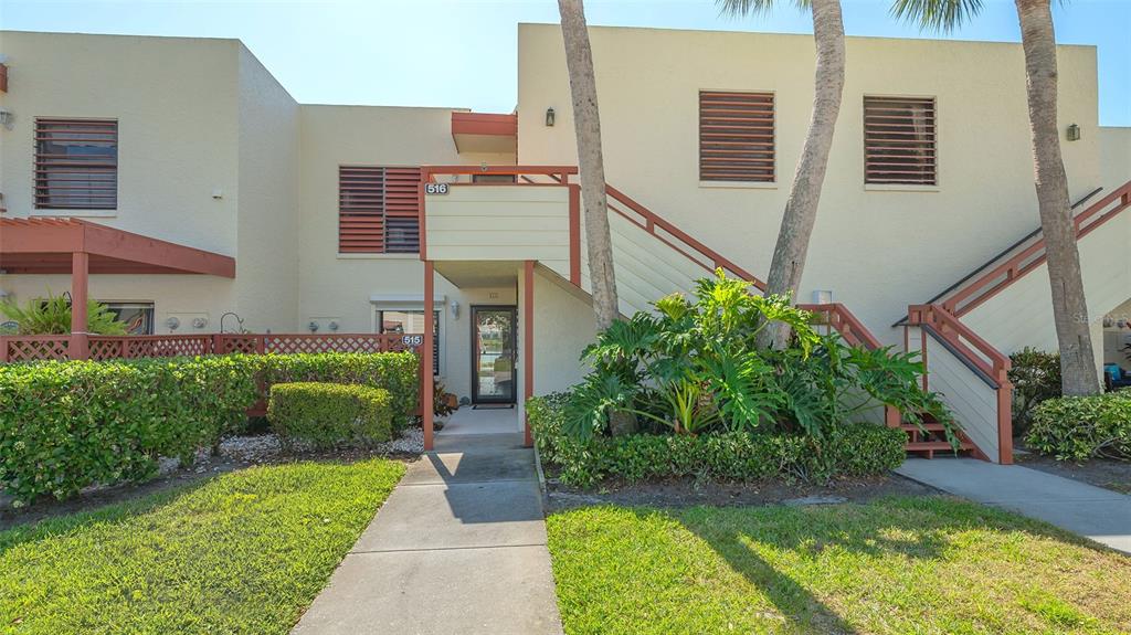 A two-story stucco townhouse exterior features a walkway, stairs, and lush landscaping — 515 SPRING LAKES BOULEVARD UNIT 515, BRADENTON, FL