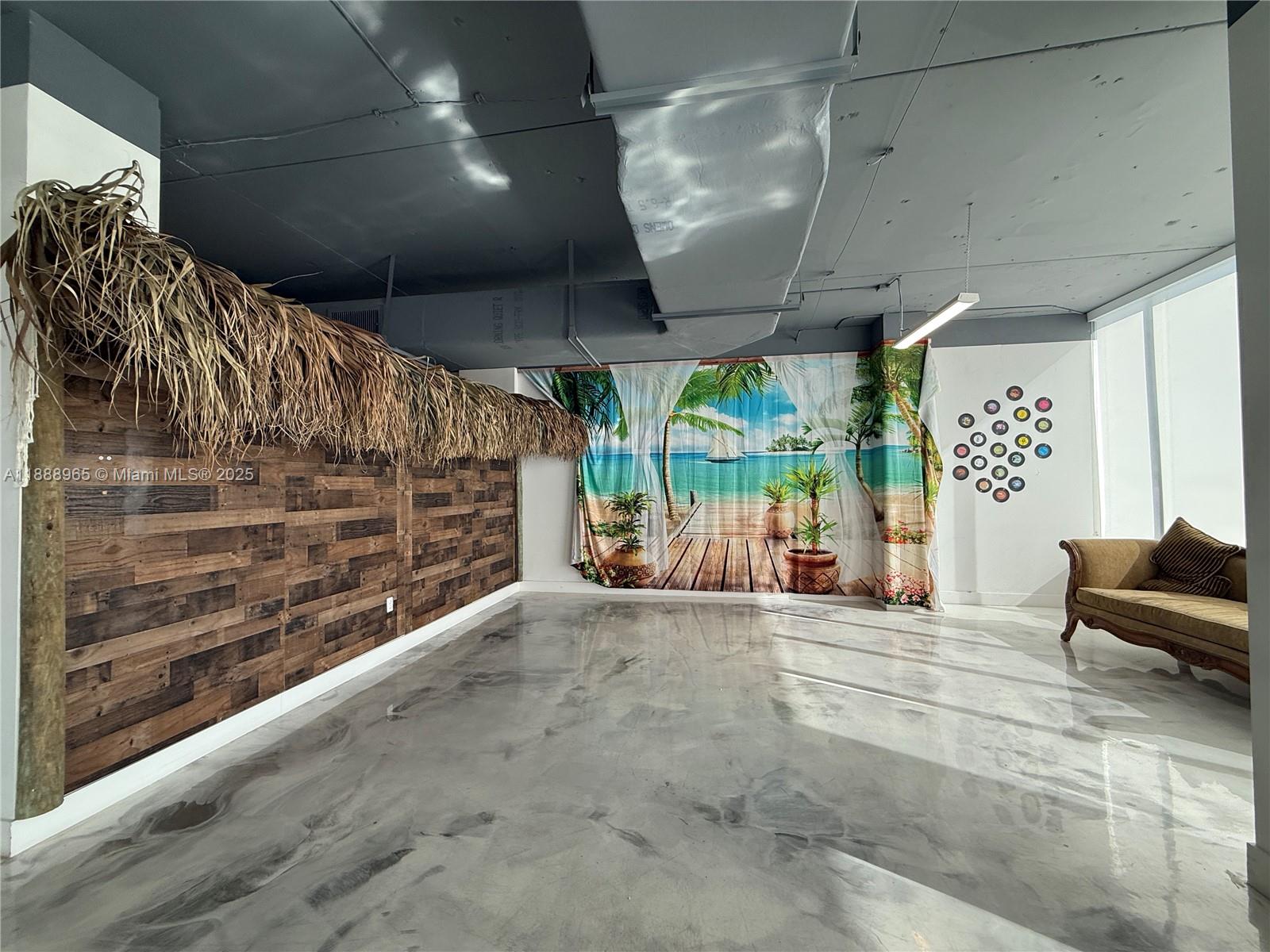 An interior room features a thatched roof accent, wood-paneled wall, beach-themed curtain, and polished floor — 42 NW 27th Ave # 302, Miami FL 33125, MIAMI, FL