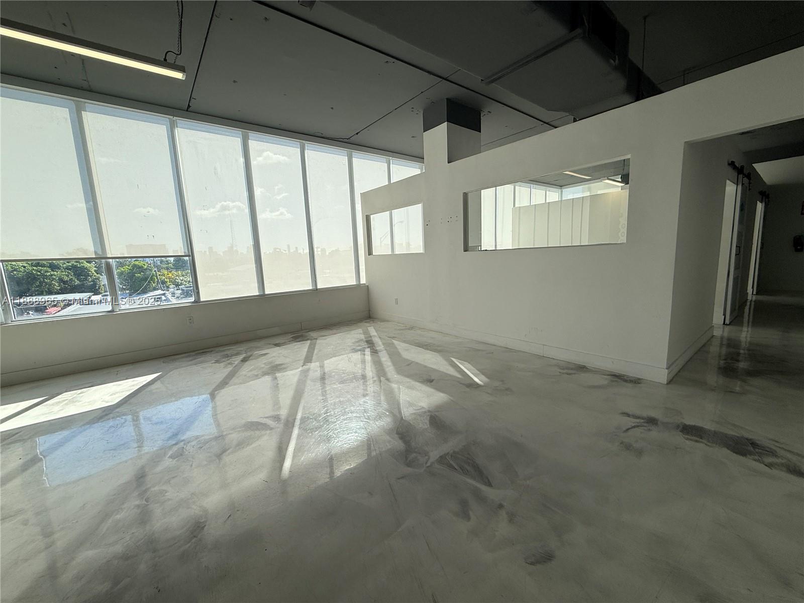 An empty office space features large windows, white walls, and a polished concrete floor — 42 NW 27th Ave # 302, Miami FL 33125, MIAMI, FL