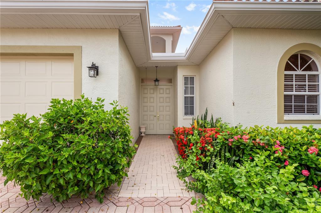 The exterior of a house features a paved walkway leading to a double front door — 4561 MURCIA BOULEVARD UNIT 13, SARASOTA, FL
