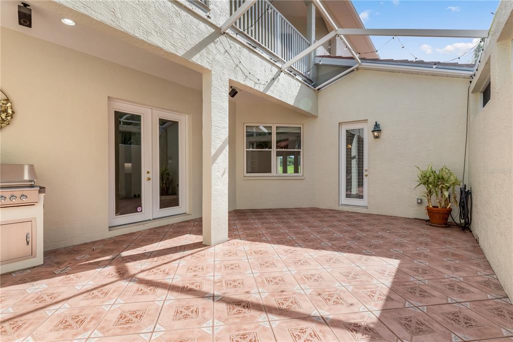 A tiled outdoor patio features a built-in grill, two glass doors, and a window — 4561 MURCIA BOULEVARD UNIT 13, SARASOTA, FL