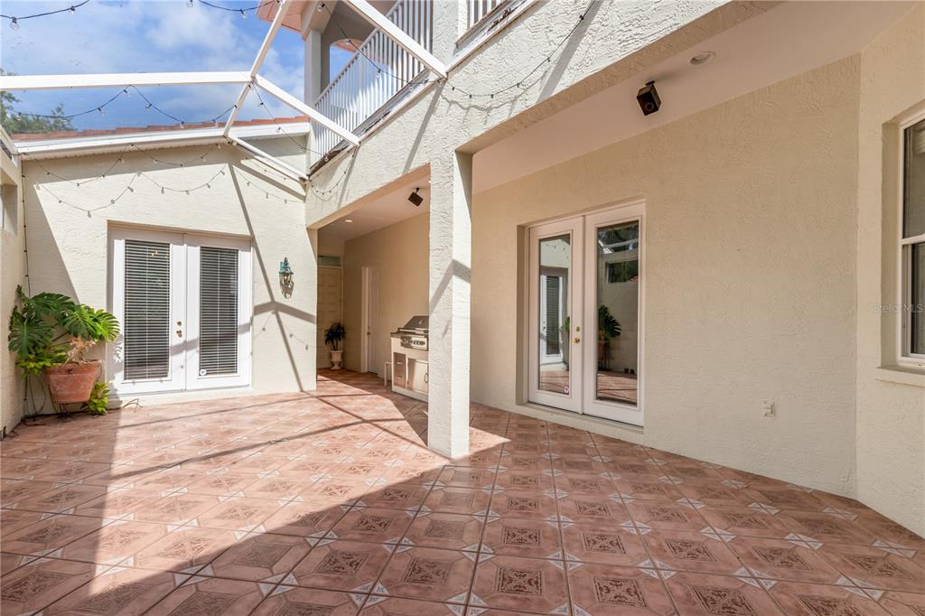 A tiled outdoor patio features a covered area, a grill, and two sets of French doors — 4561 MURCIA BOULEVARD UNIT 13, SARASOTA, FL