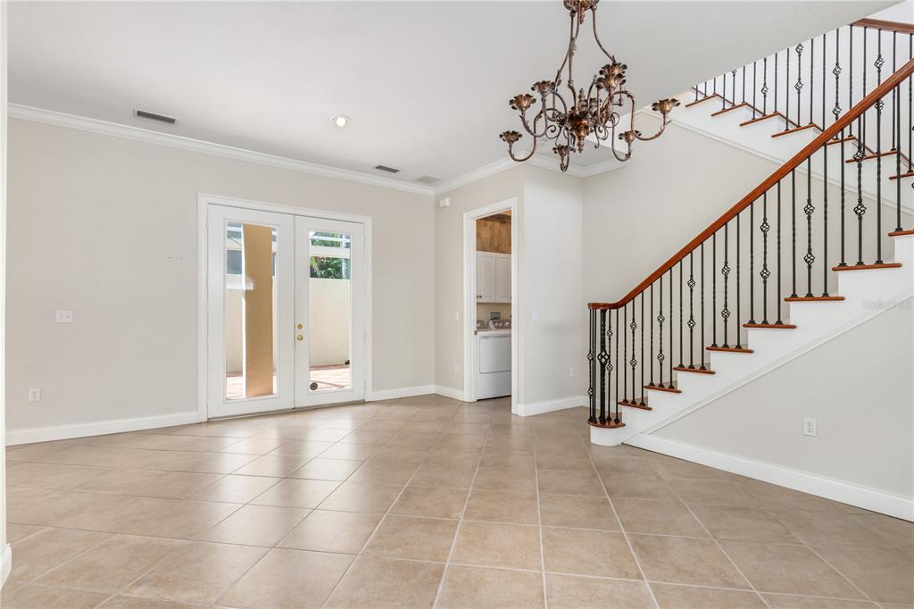 An empty room with tile flooring, a staircase with iron railings, and glass patio doors — 4561 MURCIA BOULEVARD UNIT 13, SARASOTA, FL