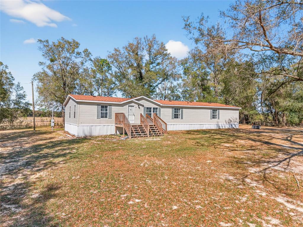A single-story manufactured home with light siding and a red roof sits on a lot — 10427 NW 8TH LANE, OCALA, FL