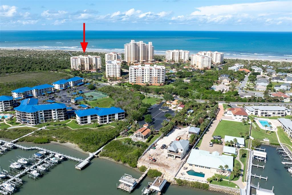 An aerial view shows a coastal resort area with multi-story buildings, a marina, and oceanfront beaches — 261 MINORCA BEACH WAY UNIT 201, NEW SMYRNA BEACH, FL