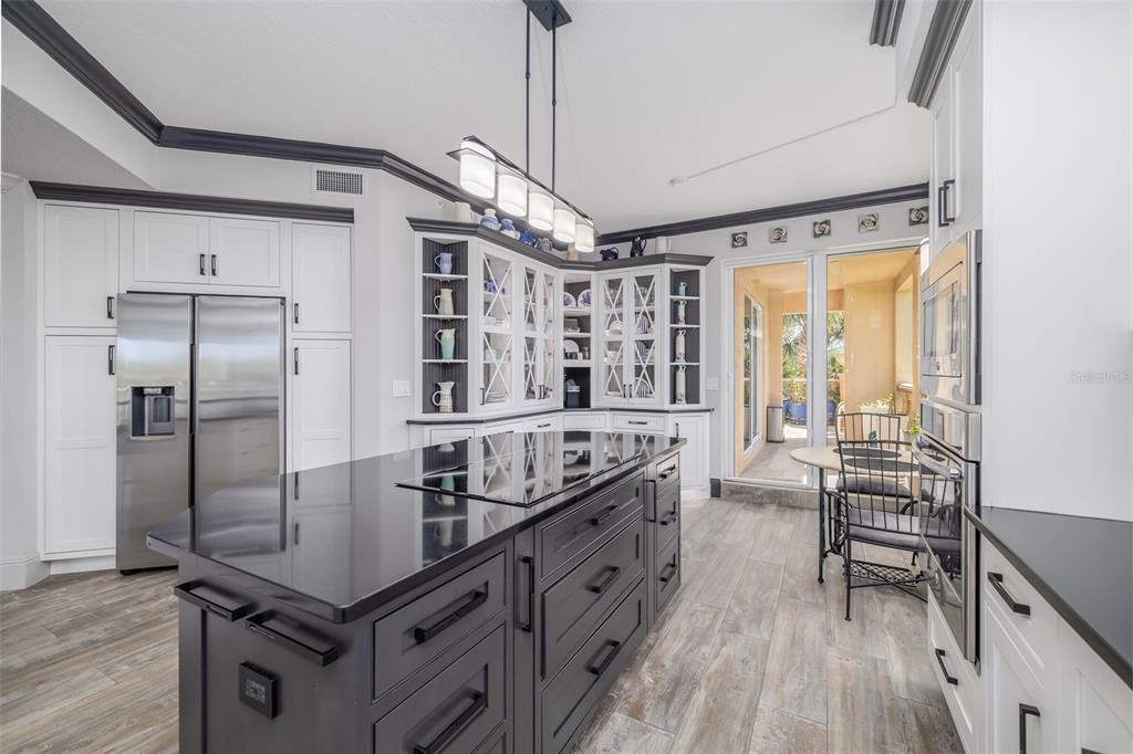 A kitchen with a black island, white cabinets, stainless steel appliances, and wood-look tile flooring — 261 MINORCA BEACH WAY UNIT 201, NEW SMYRNA BEACH, FL