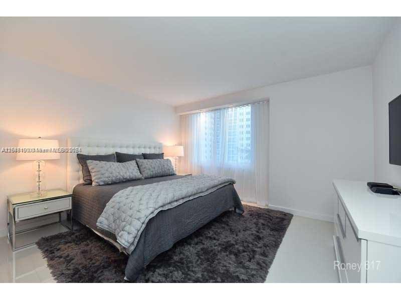 A bedroom features a tufted headboard, gray bedding, a shaggy rug, and a white dresser — 2301 Collins Ave # 617, Miami Beach FL 33139, MIAMI BEACH, FL