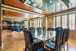 A dining room features a glass table, patterned chairs, and a mirrored ceiling tray — 11111 Biscayne Blvd # 227, North Miami Beach FL 33181, NORTH MIAMI BEACH, FL