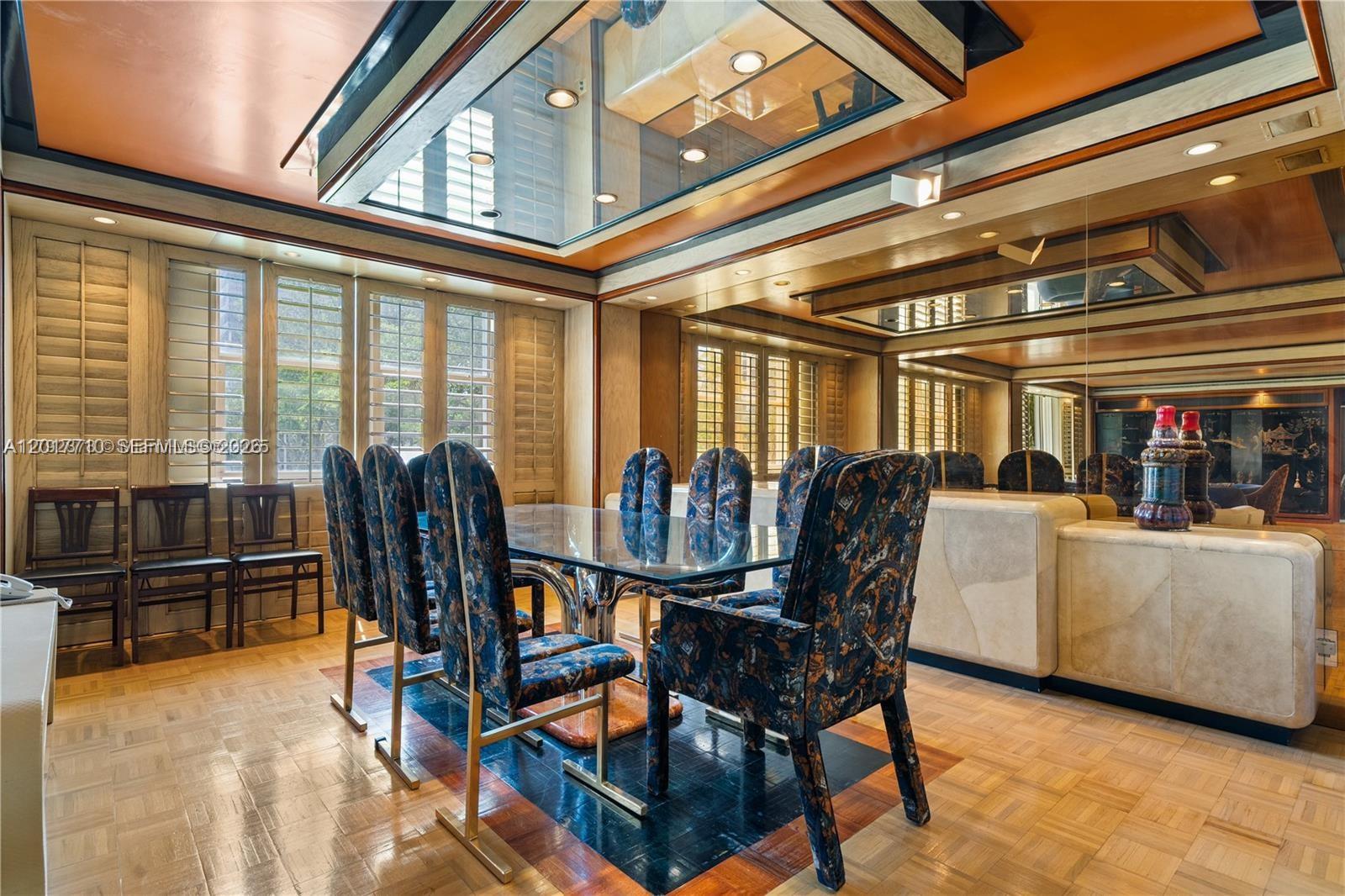A dining room features a glass table, patterned chairs, wood flooring, and a mirrored wall — 11111 Biscayne Blvd # 227, North Miami Beach FL 33181, NORTH MIAMI BEACH, FL