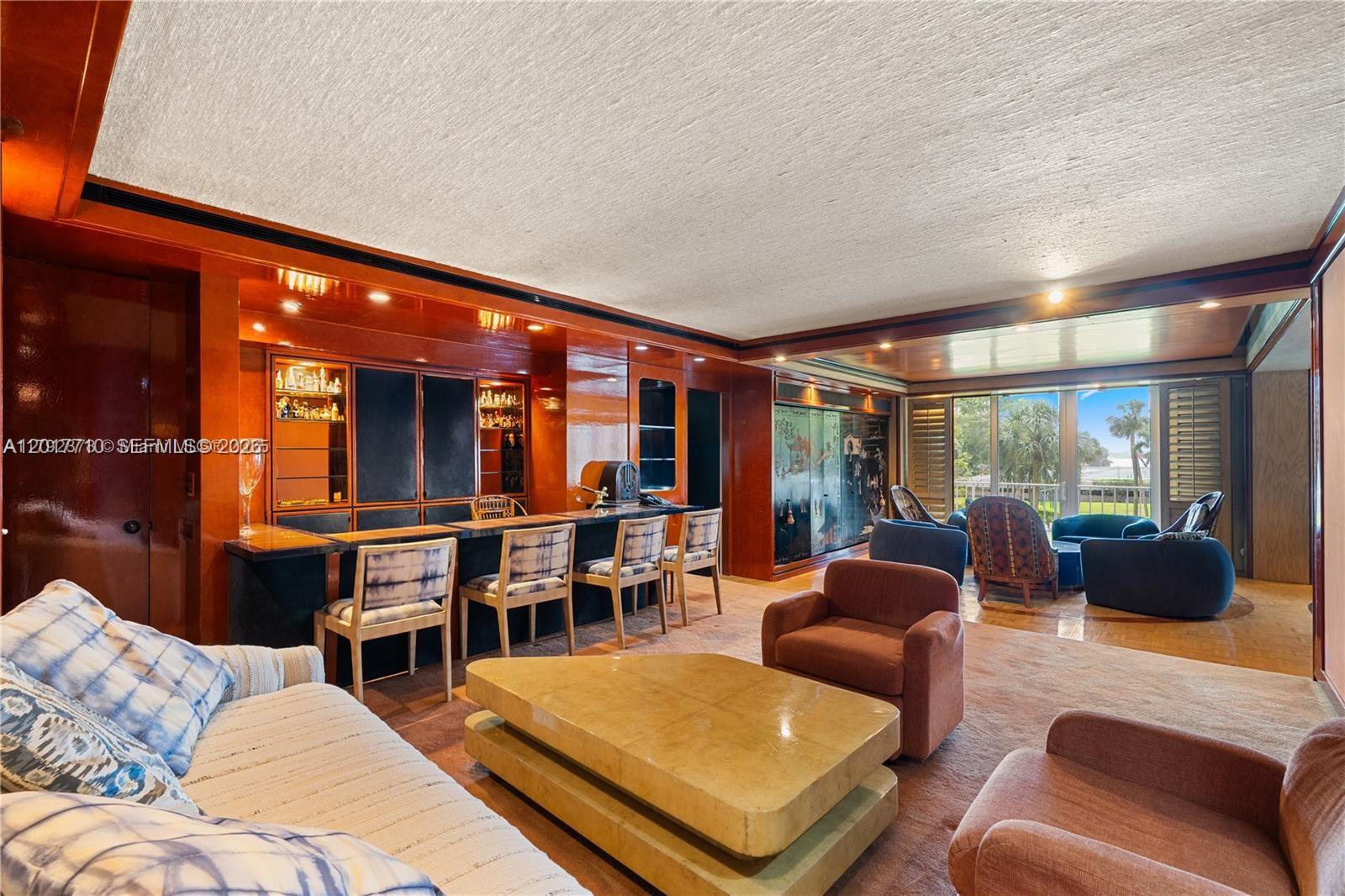 A living room features a built-in wooden bar, a central coffee table, and patio access — 11111 Biscayne Blvd # 227, North Miami Beach FL 33181, NORTH MIAMI BEACH, FL