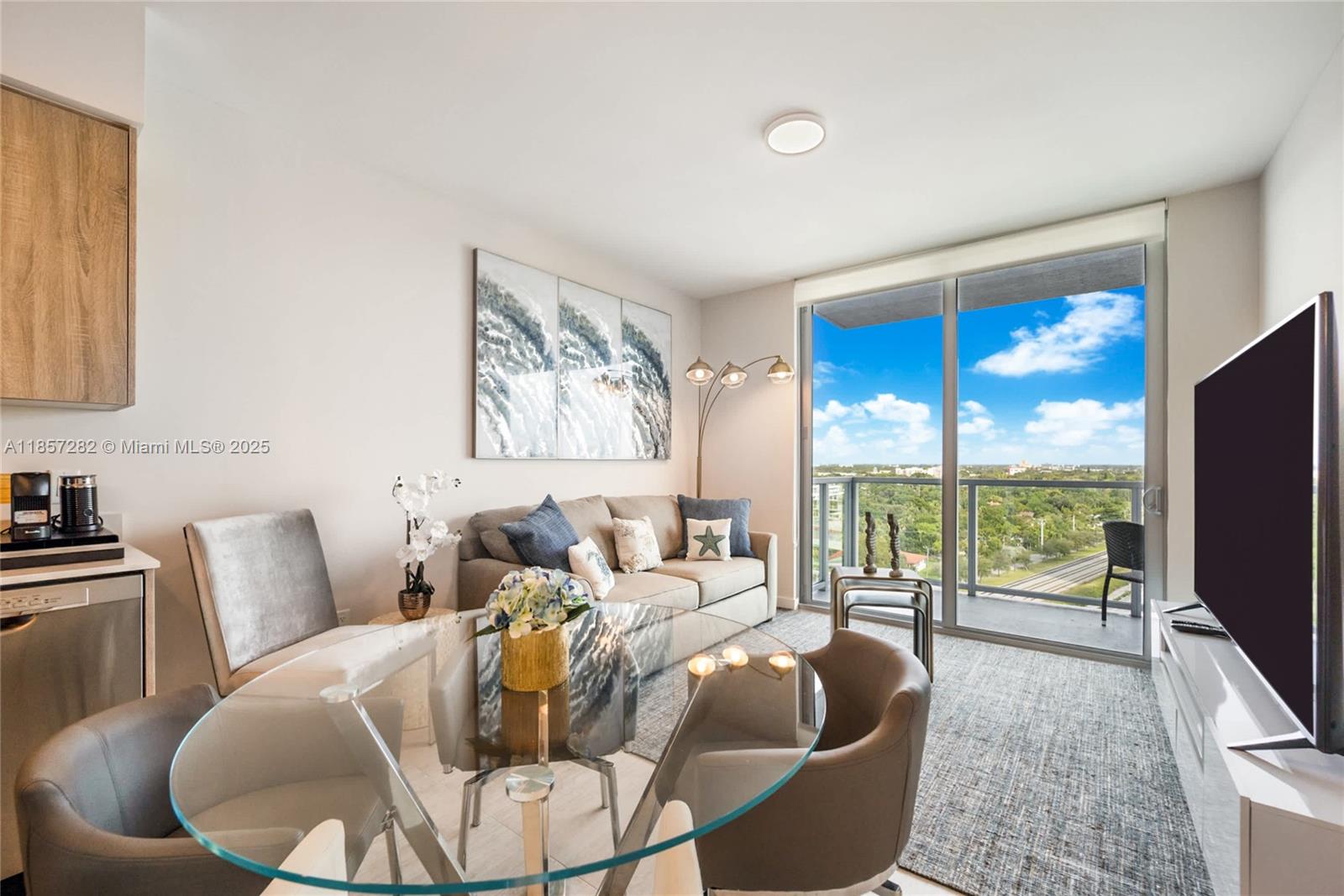 A living and dining area features a glass table, gray sofa, and balcony with views — 3900 Biscayne Blvd # 1009, Miami FL 33137, MIAMI, FL