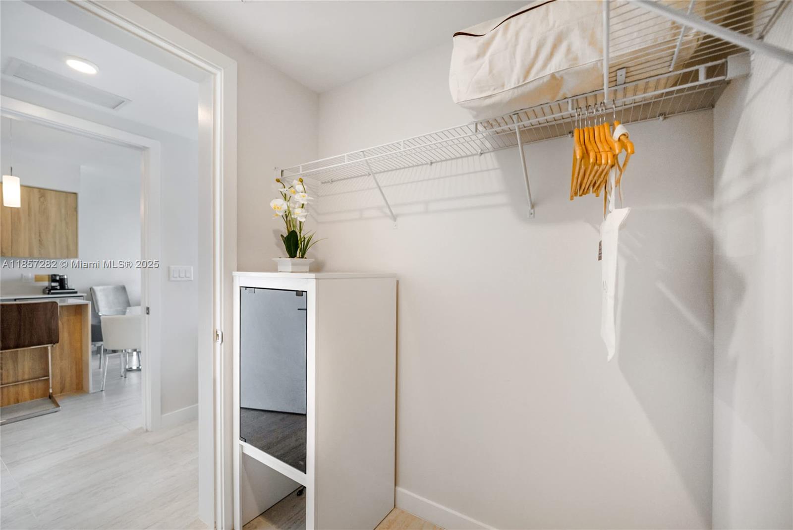 A closet features a wire shelf, a white storage cabinet, and a view into a kitchen — 3900 Biscayne Blvd # 1009, Miami FL 33137, MIAMI, FL