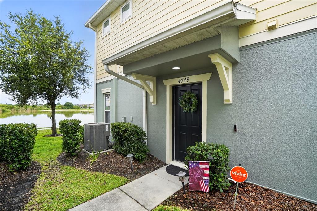 The exterior of a two-story home features a gray stucco facade, a black front door, and a small porch — 4749 SOMERSET HILL LANE, RIVERVIEW, FL