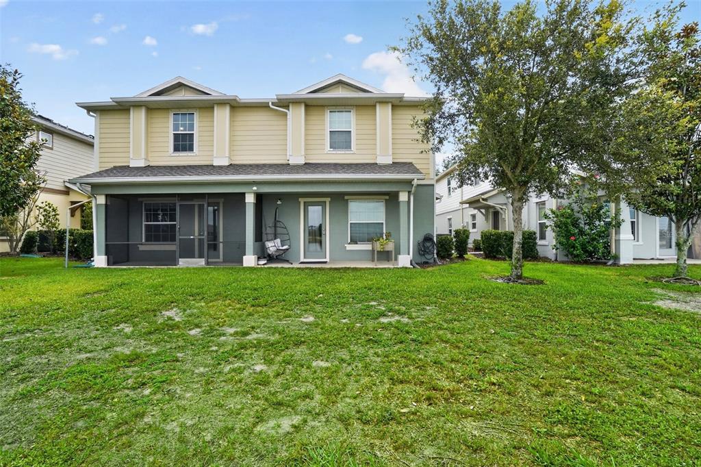 The exterior rear view of a two-story house features a screened-in patio and lawn — 4749 SOMERSET HILL LANE, RIVERVIEW, FL