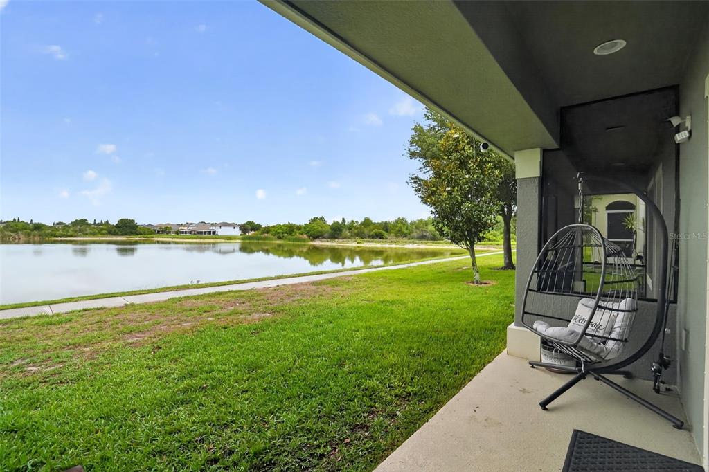 A covered patio overlooks a grassy lawn and a lake under a blue sky — 4749 SOMERSET HILL LANE, RIVERVIEW, FL