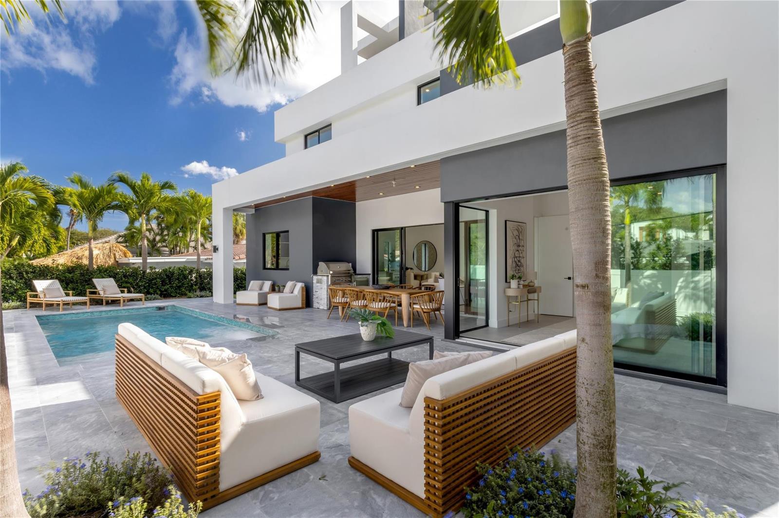 A modern patio features a swimming pool, outdoor seating, and a dining area — 3205 Leigh Road, Pompano Beach FL 33062, POMPANO BEACH, FL