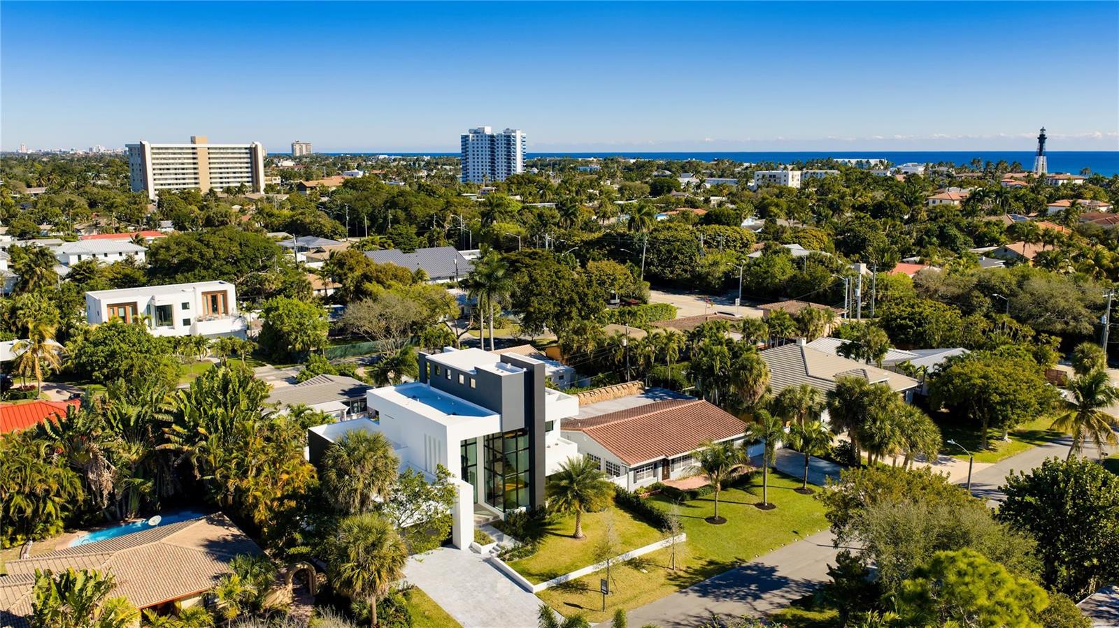 An aerial view shows a modern white and gray house surrounded by lush tropical landscaping — 3205 Leigh Road, Pompano Beach FL 33062, POMPANO BEACH, FL