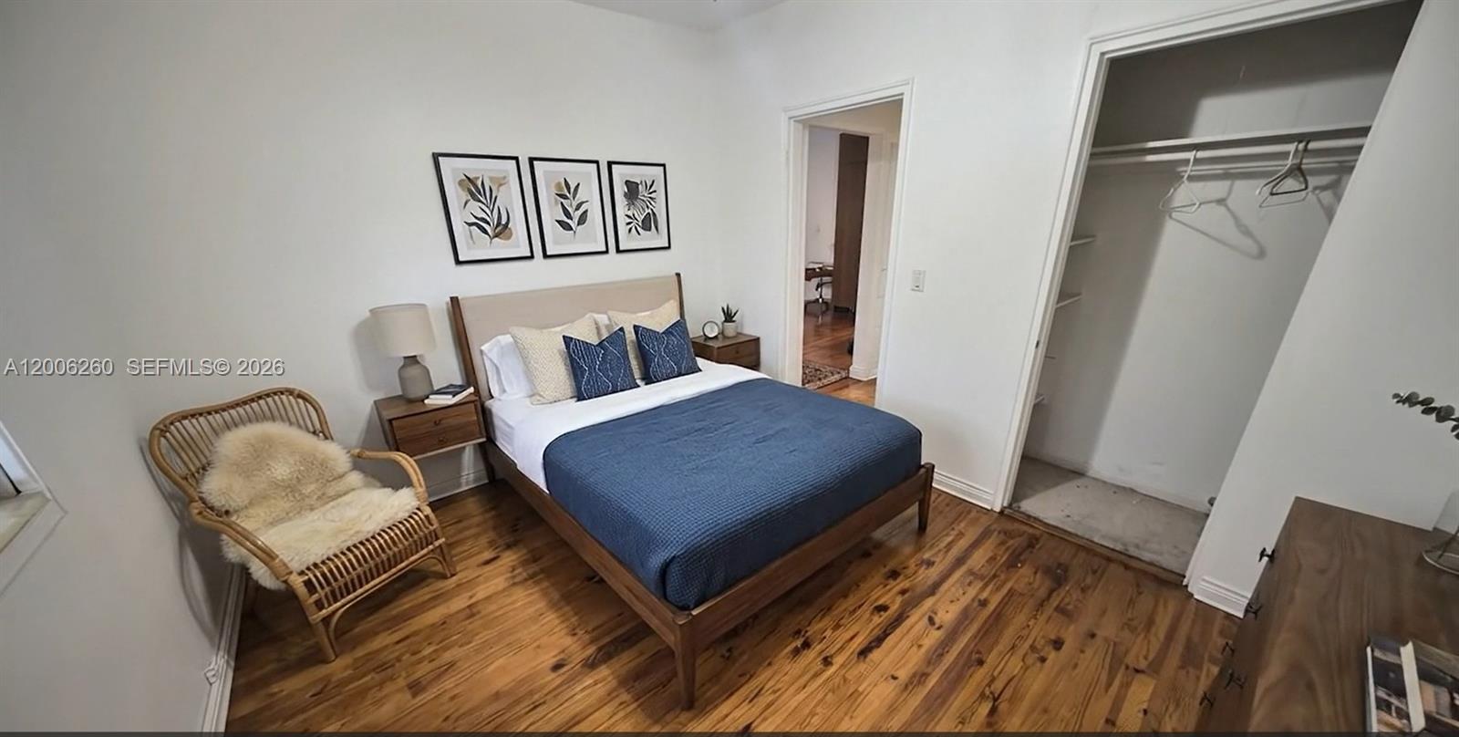 A bedroom features a bed with a blue quilt, wood flooring, and an open closet — 4740 Pine Tree Dr # 20, Miami Beach FL 33140, MIAMI BEACH, FL