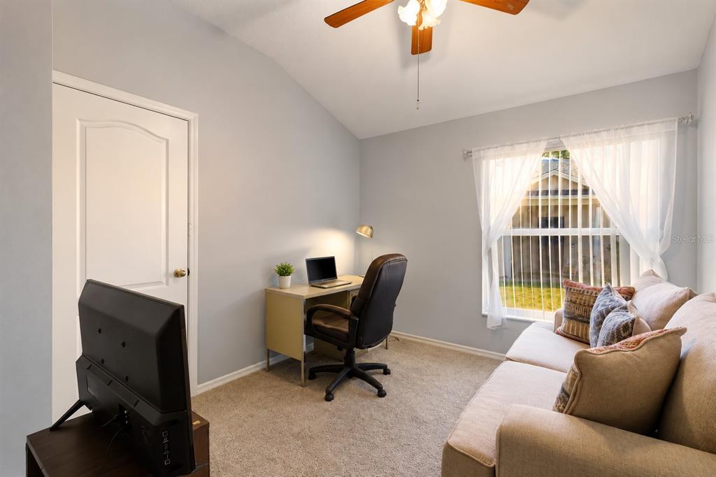 A home office with a desk, chair, sofa, and television under a ceiling fan — 30907 WHITLOCK DRIVE, WESLEY CHAPEL, FL