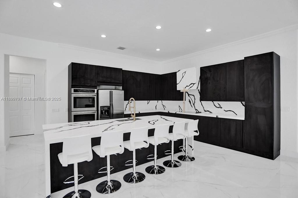 A modern kitchen features dark cabinetry, a white marble island, and matching marble flooring — 3152 SW 147th Ave, Davie FL 33330, DAVIE, FL