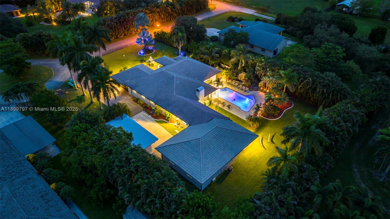 An aerial view shows a house with a pool, palm trees, and landscaped grounds at night — 3152 SW 147th Ave, Davie FL 33330, DAVIE, FL