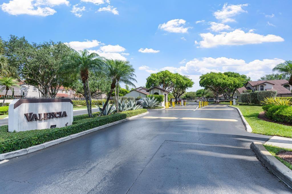 The gated entrance to the Valencia community features a stone sign, palm trees, and landscaping — 10091 SW 137th Pl, Miami FL 33186, MIAMI, FL