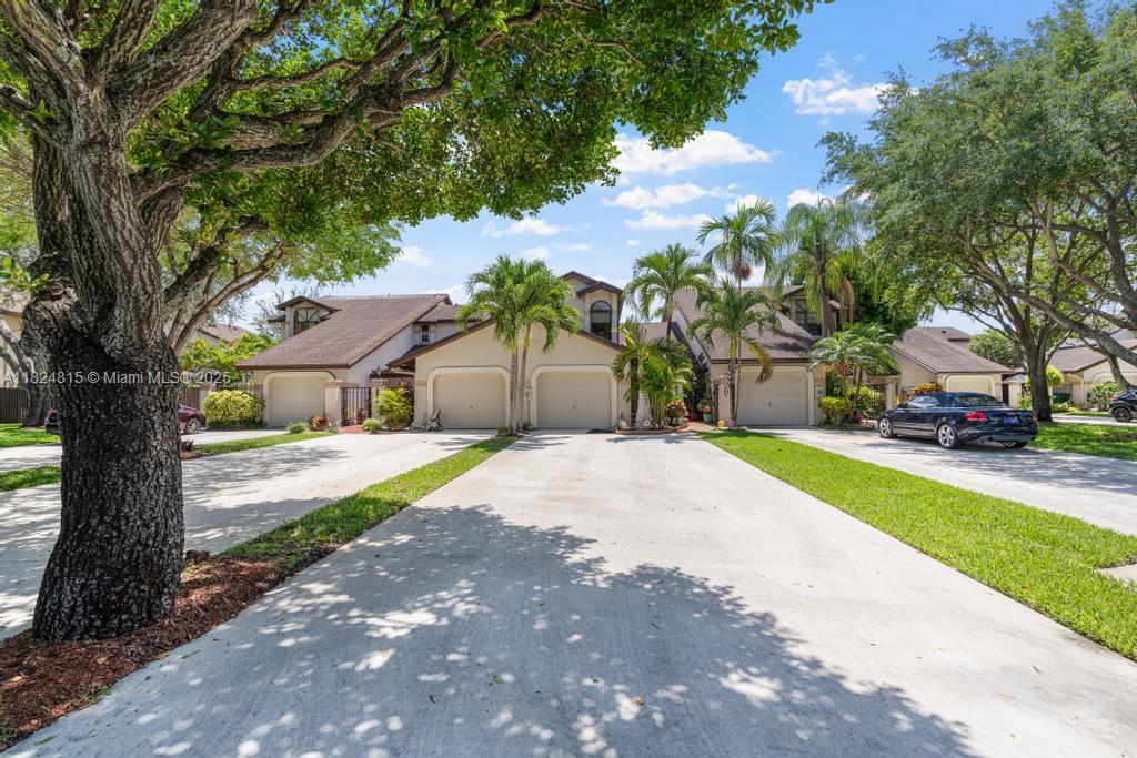 A view of a multi-unit residential building with attached garages and a large driveway — 10091 SW 137th Pl, Miami FL 33186, MIAMI, FL
