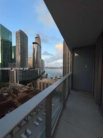 A balcony with a glass railing overlooks a city skyline and a body of water — 77 SE 5th St # 2004, Miami FL 33131, MIAMI, FL