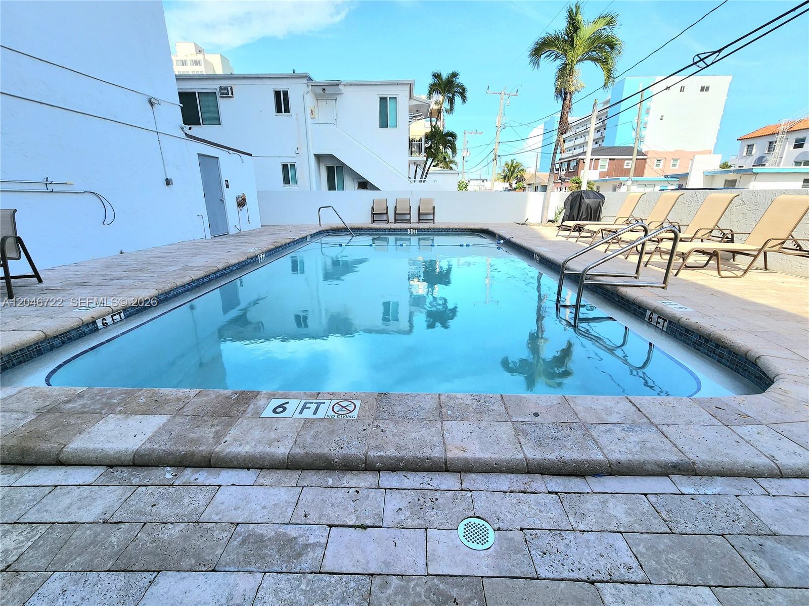 An outdoor swimming pool is surrounded by a stone deck and lounge chairs — 211 S Ocean Dr # 501, Hollywood FL 33019, HOLLYWOOD, FL