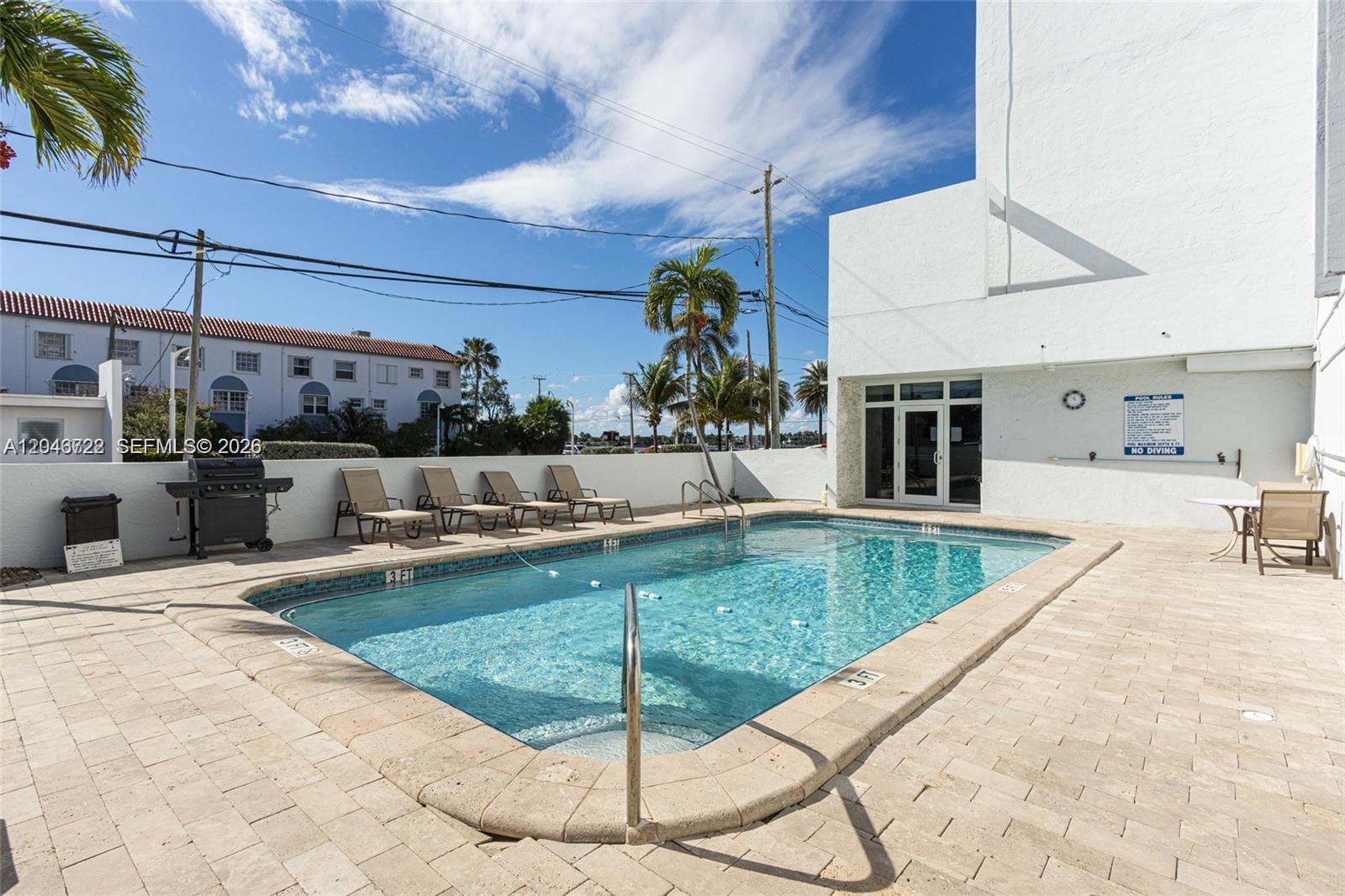 A rectangular swimming pool is surrounded by a paved deck with lounge chairs and a grill — 211 S Ocean Dr # 501, Hollywood FL 33019, HOLLYWOOD, FL