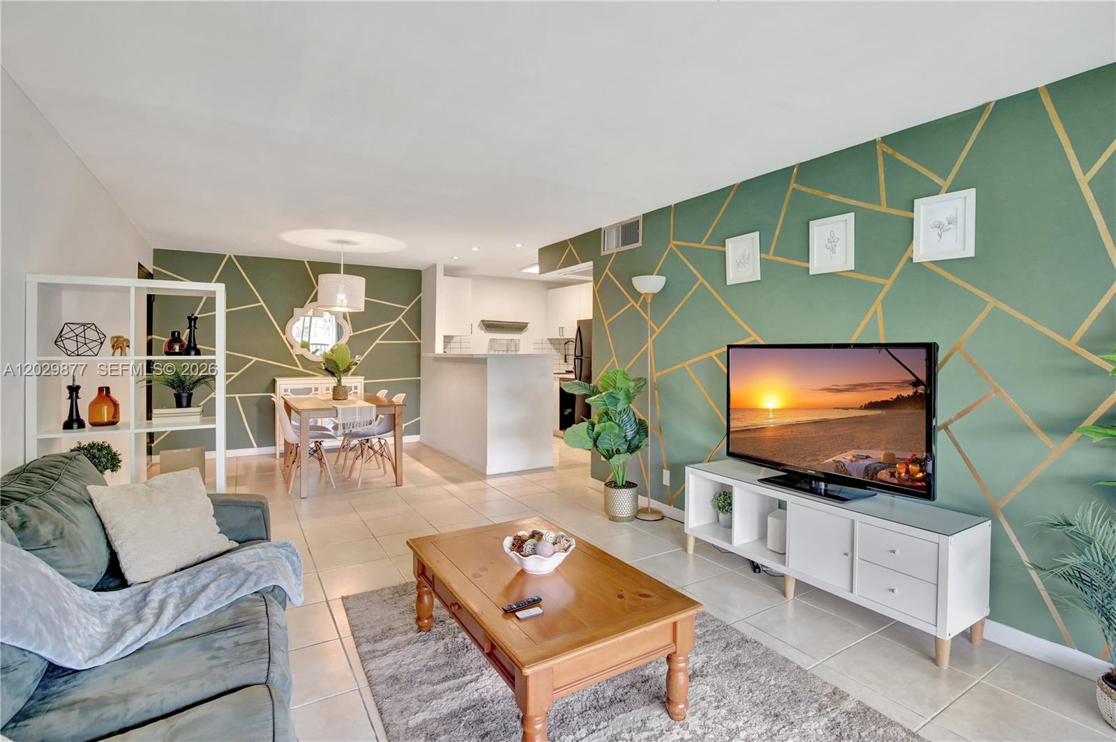 A living room features sage green walls with gold geometric lines, tile flooring, and furniture — 5821 Washington St # 30, Hollywood FL 33023, HOLLYWOOD, FL