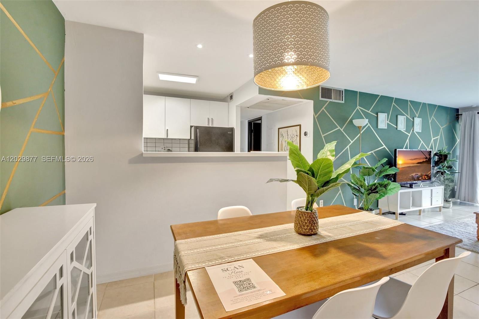 A dining area with a wooden table and chairs sits before a kitchen pass-through window — 5821 Washington St # 30, Hollywood FL 33023, HOLLYWOOD, FL