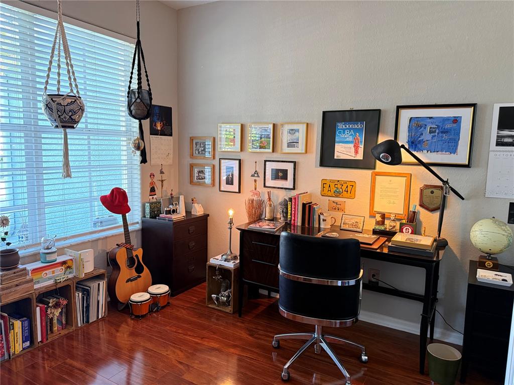 A home office features a dark wood desk, a black chair, and a gallery wall — 10703 BANFIELD DRIVE, RIVERVIEW, FL