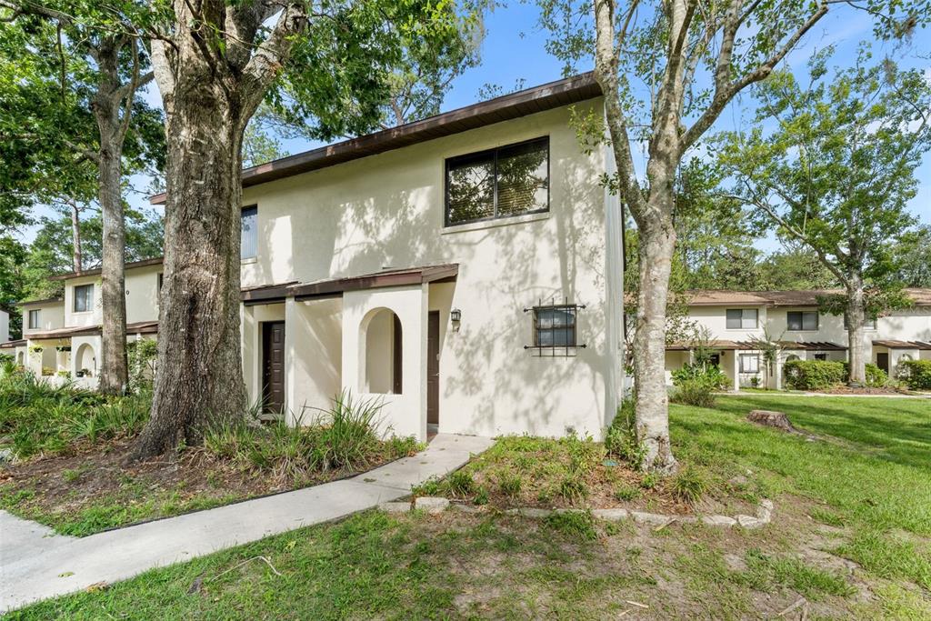 A two-story stucco townhouse with a covered entryway and mature trees in the front yard — 2635 SW 35TH PLACE UNIT 307, GAINESVILLE, FL