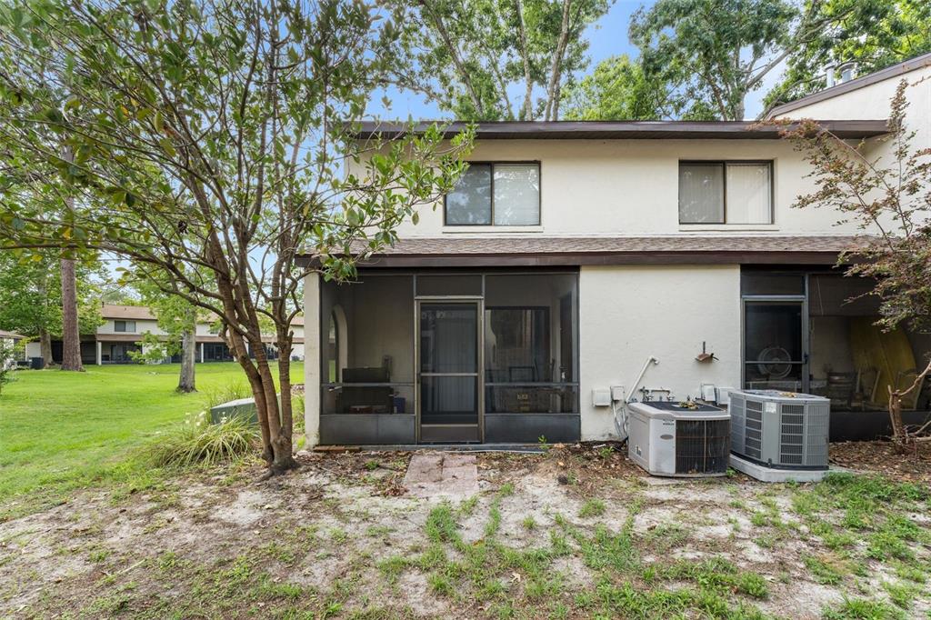 The exterior rear view of a two-story townhouse shows a screened patio and HVAC unit — 2635 SW 35TH PLACE UNIT 307, GAINESVILLE, FL