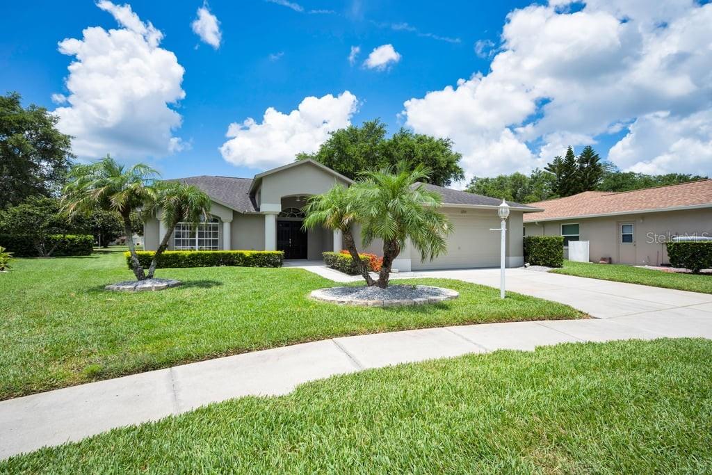 A single-story house with a beige exterior, a two-car garage, and two palm trees — 1253 EVENINGSIDE COURT, TRINITY, FL