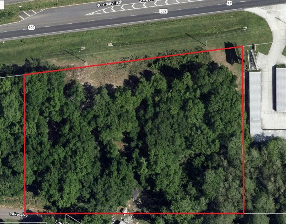 An aerial view shows a rectangular, tree-covered vacant lot outlined in red near a highway — S ORANGE BLOSSOM TRAIL, KISSIMMEE, FL