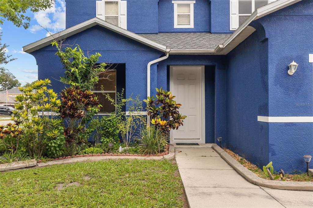 The exterior of a blue house features a white front door and a concrete walkway — 402 VINE CLIFF STREET, RUSKIN, FL