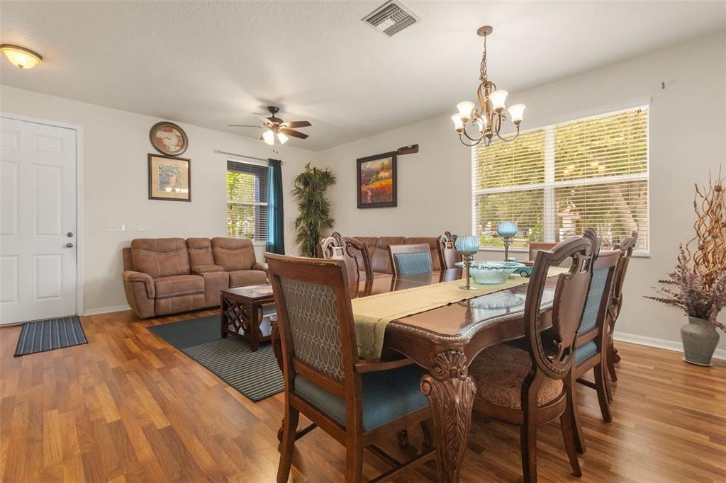 A dining area and living room with wood-look flooring, a chandelier, and a ceiling fan — 402 VINE CLIFF STREET, RUSKIN, FL