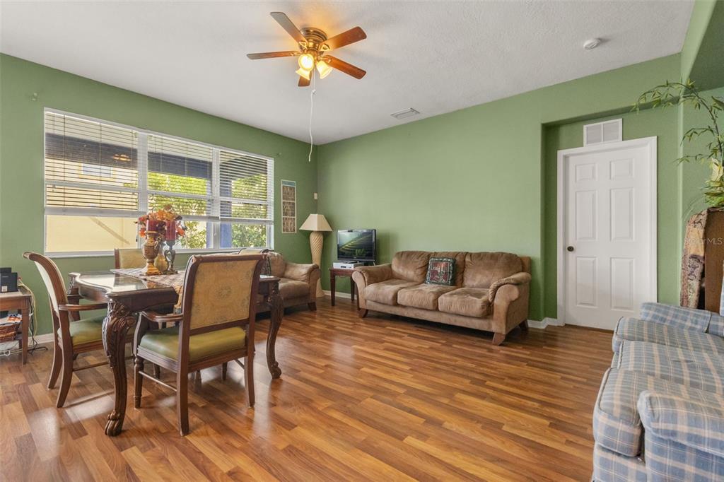 A living and dining room with green walls, wood flooring, and a ceiling fan — 402 VINE CLIFF STREET, RUSKIN, FL