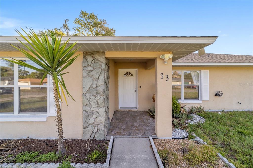 The exterior of a single-story house features a stone-accented entryway and a white front door — 33 PECAN RUN PASS, OCALA, FL
