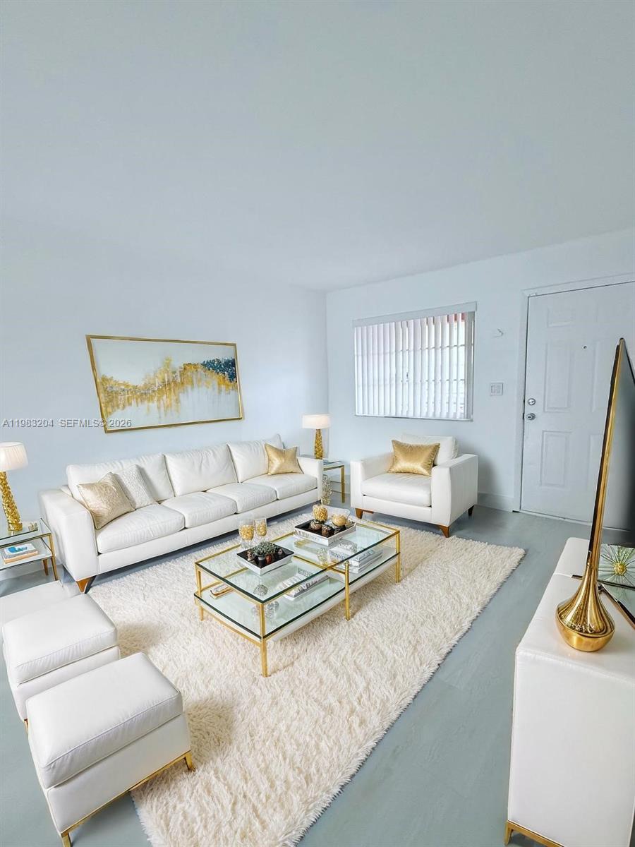 A bright living room features white furniture, a glass coffee table, and gold accents — 6801 W 36th Ave # 102, Hialeah FL 33018, HIALEAH, FL