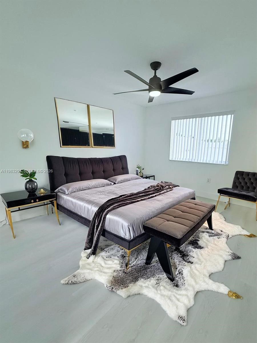 A modern bedroom features a black upholstered bed, a cowhide rug, and a ceiling fan — 6801 W 36th Ave # 102, Hialeah FL 33018, HIALEAH, FL