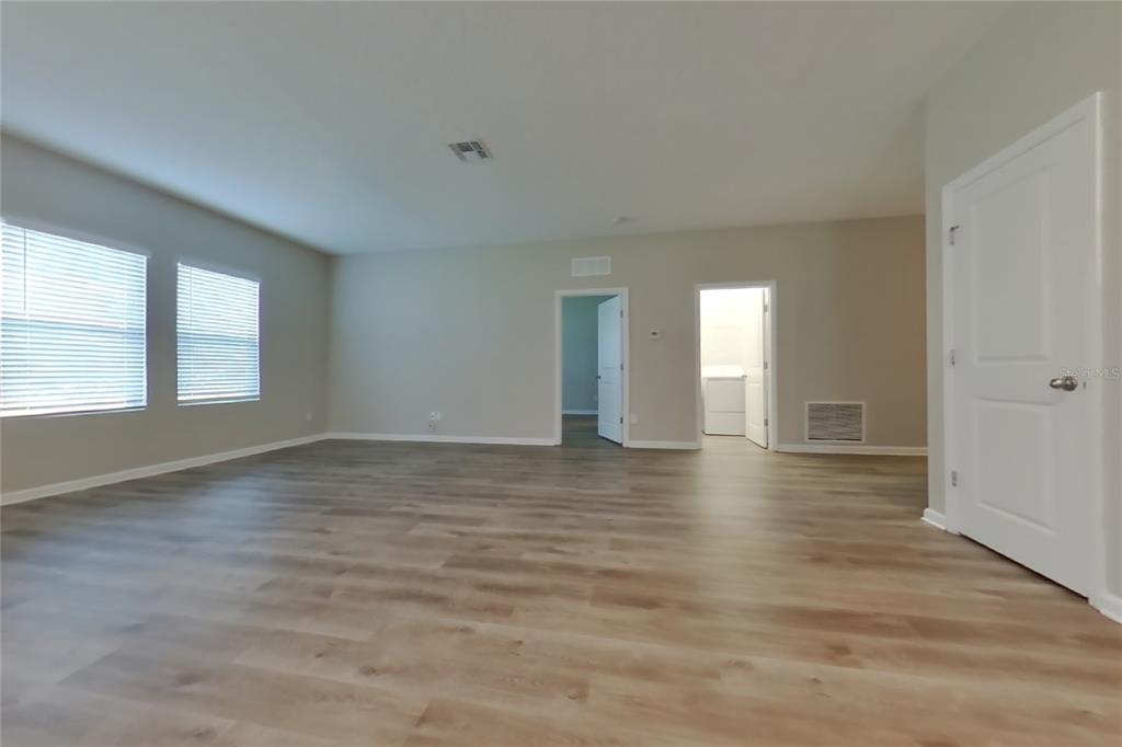 An empty room with light wood-look flooring, beige walls, and two doorways — 16517 CHERRY LANDING DRIVE, GROVELAND, FL