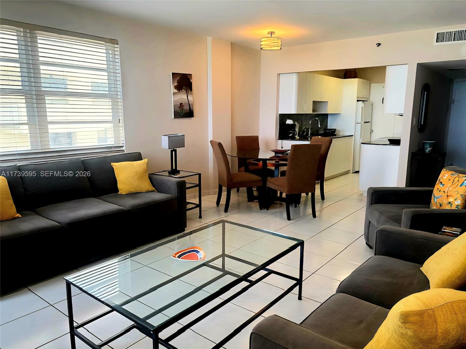 A living room and dining area feature dark gray sofas, a glass coffee table, and tile floors — 100 Lincoln Rd # 821, Miami Beach FL 33139, MIAMI BEACH, FL