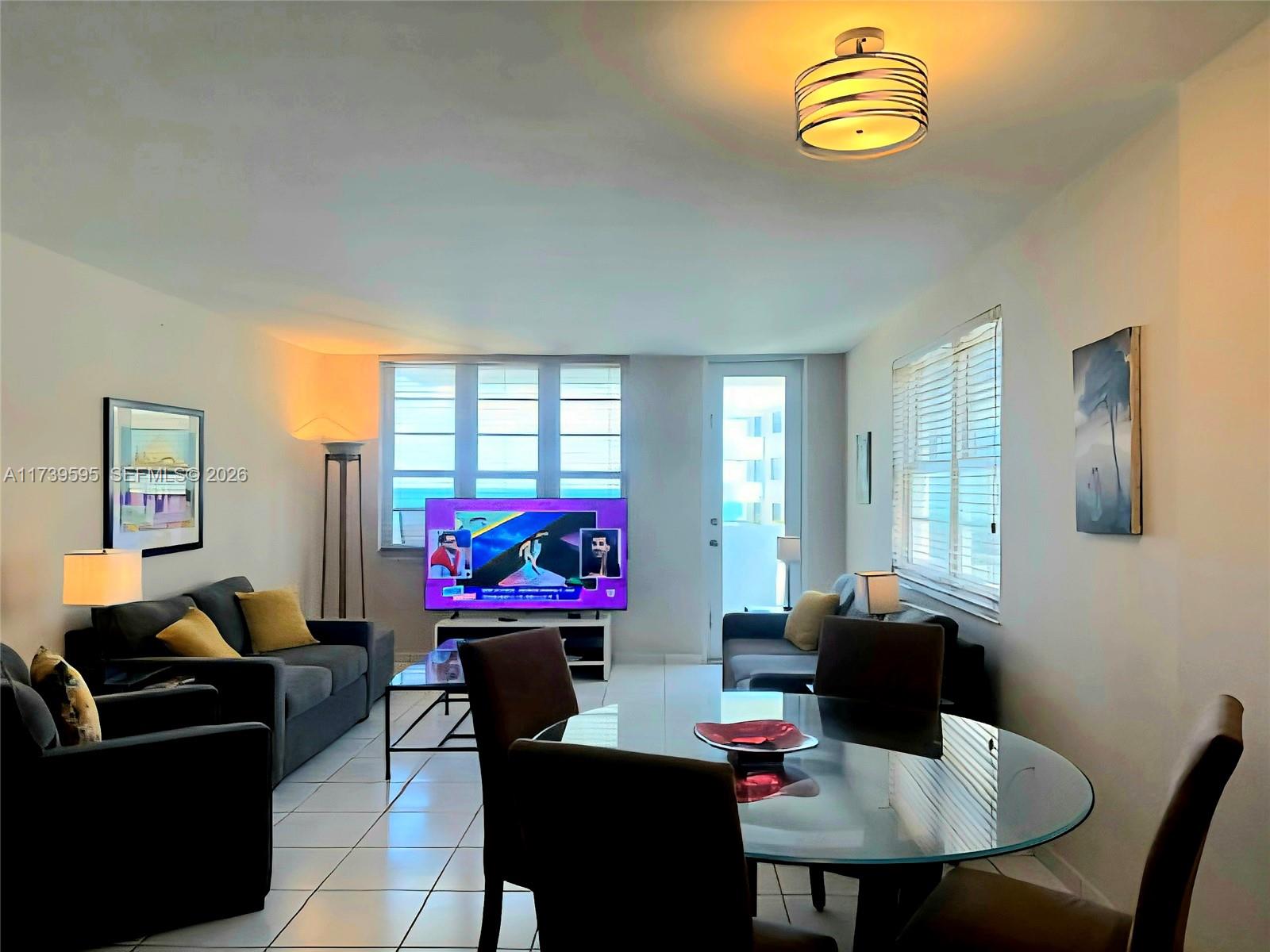 A living and dining area features tile floors, a glass table, and ocean views — 100 Lincoln Rd # 821, Miami Beach FL 33139, MIAMI BEACH, FL