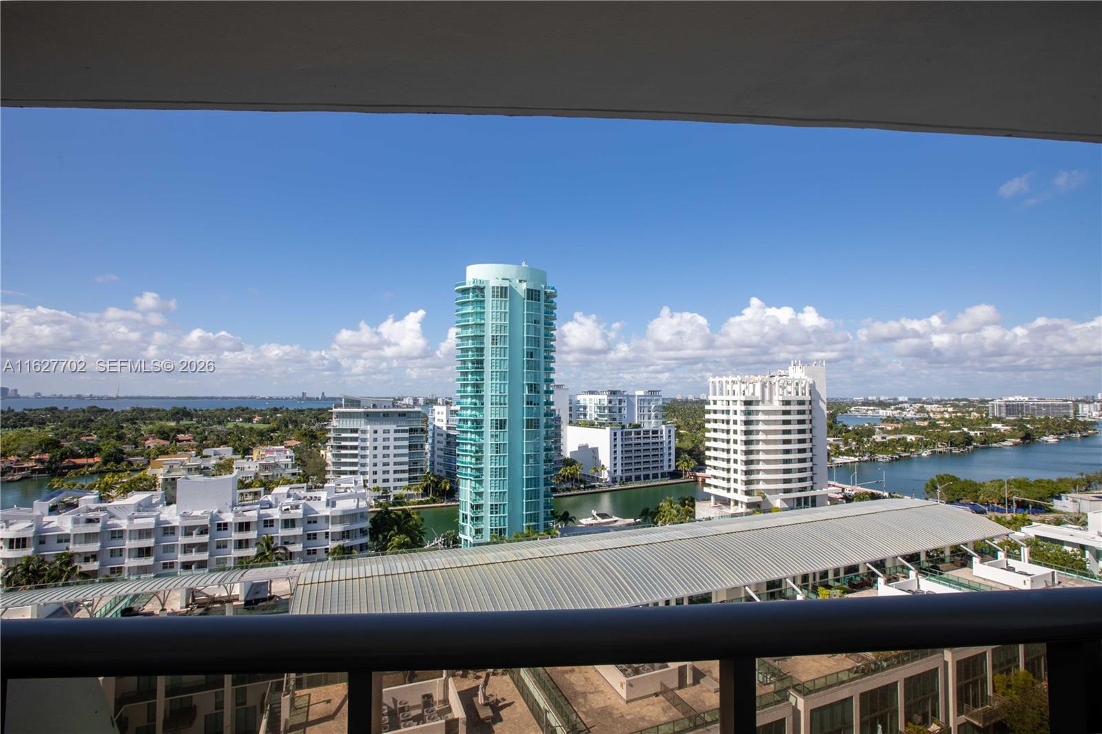 A high-angle view shows a city skyline with a prominent turquoise tower and waterfront — 6039 Collins Ave # 1728, Miami Beach FL 33140, MIAMI BEACH, FL
